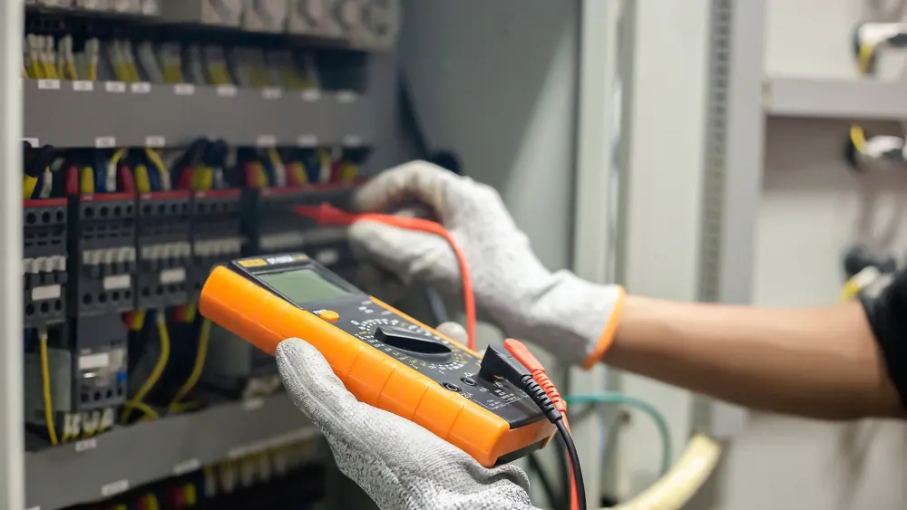 Electrician testing circuits with a multimeter as part of an EICR in Leicestershire